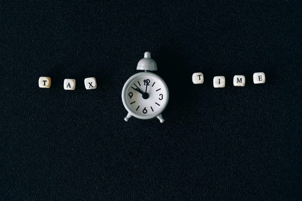 Black background with an analog clock and the words "tax" and "time" on either side. 